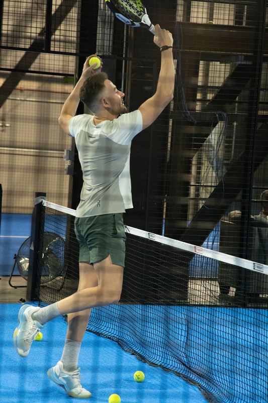 A player jumps to attack a high ball at the net