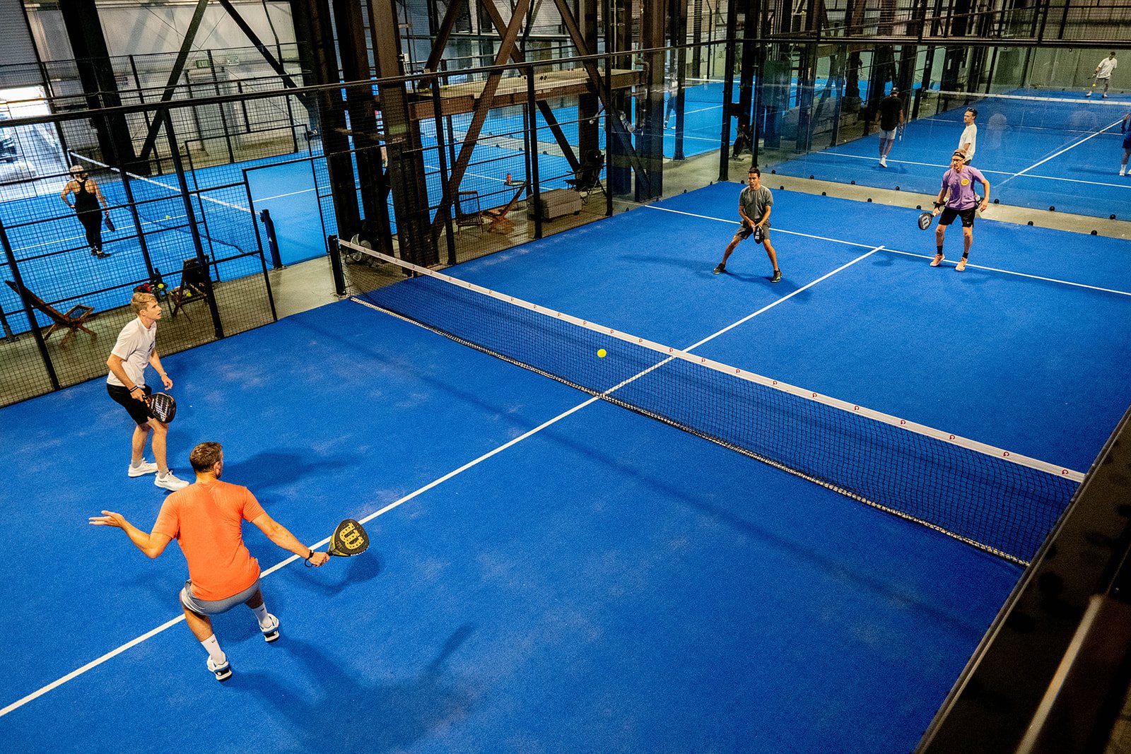 Players on adjacent courts inside Foundry Padel's converted warehouse