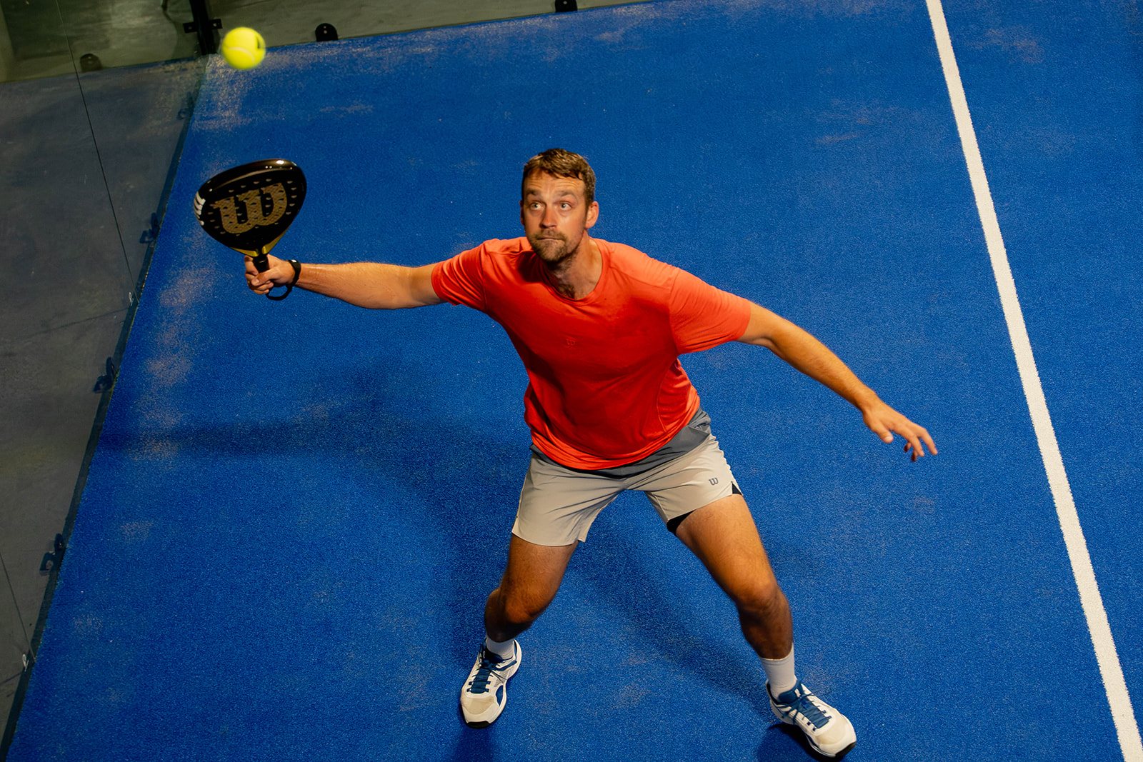 A player stretches wide for a forehand on court at Foundry Padel